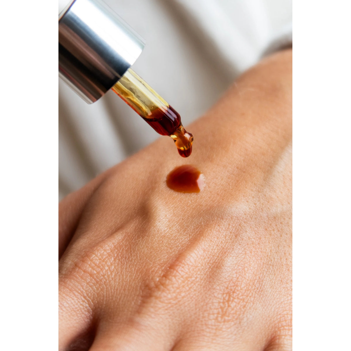 Texture de l'Huile Noire ODEN déposée sur la peau avec une pipette
